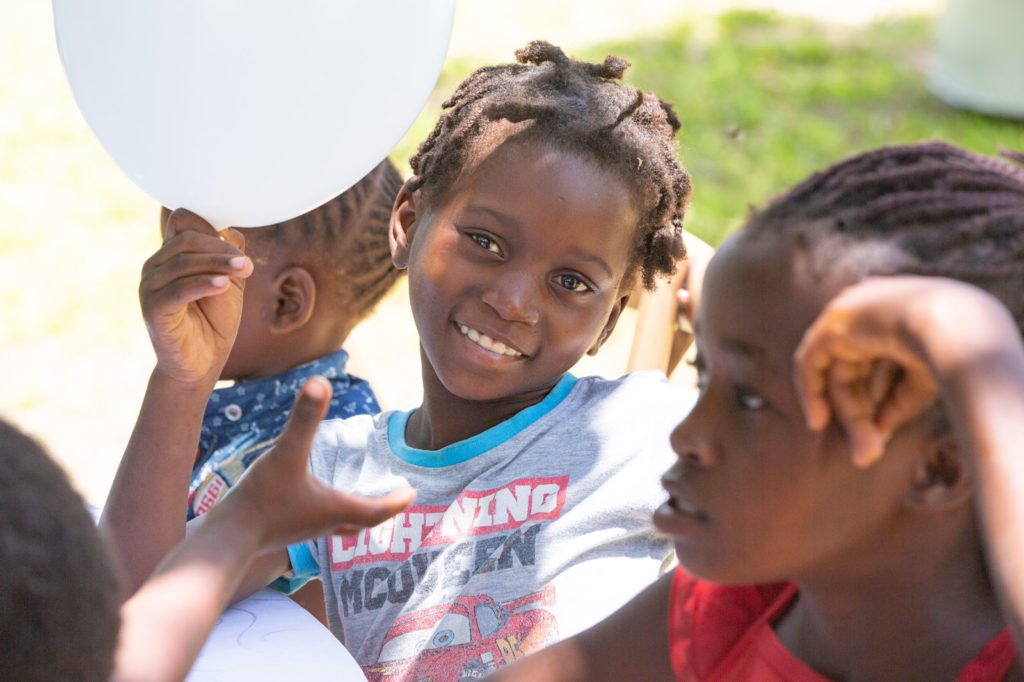 Two smiling children at Goodwill Mozambique, one holding a white balloon