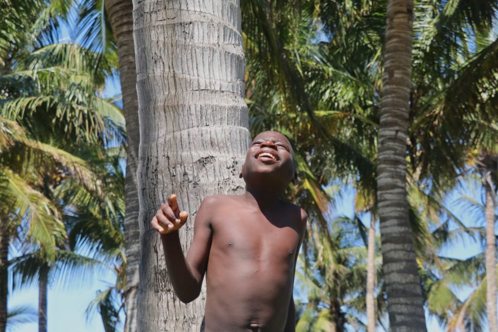 A boy laughing beside a palm tree