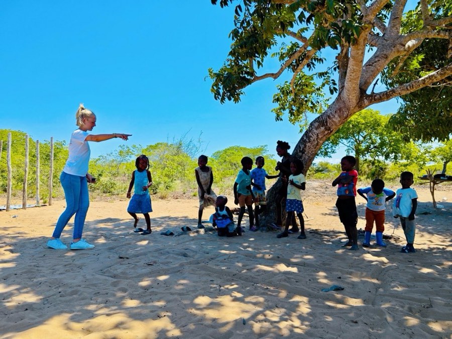 The Goodwill team and children gathered under a tree on a community outreach day
