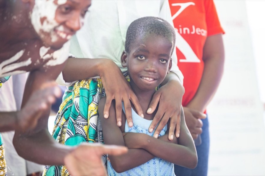 A child smiling in a caregiver’s arms on opening day