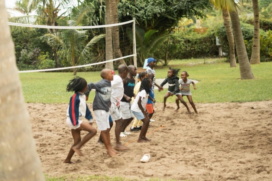 Children playing on a sandy field among palm trees