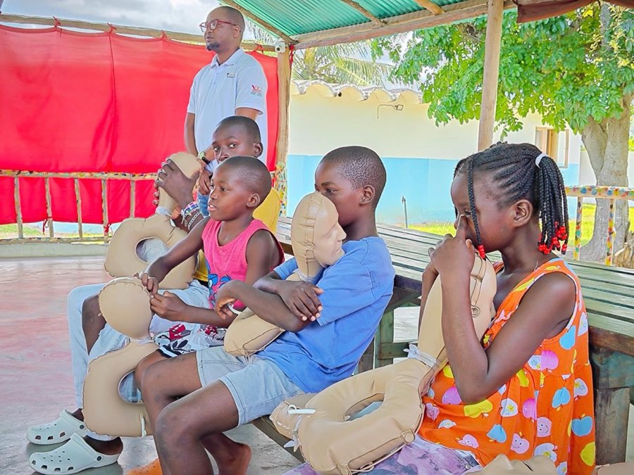 Children sitting together on a bench with a volunteer at the home