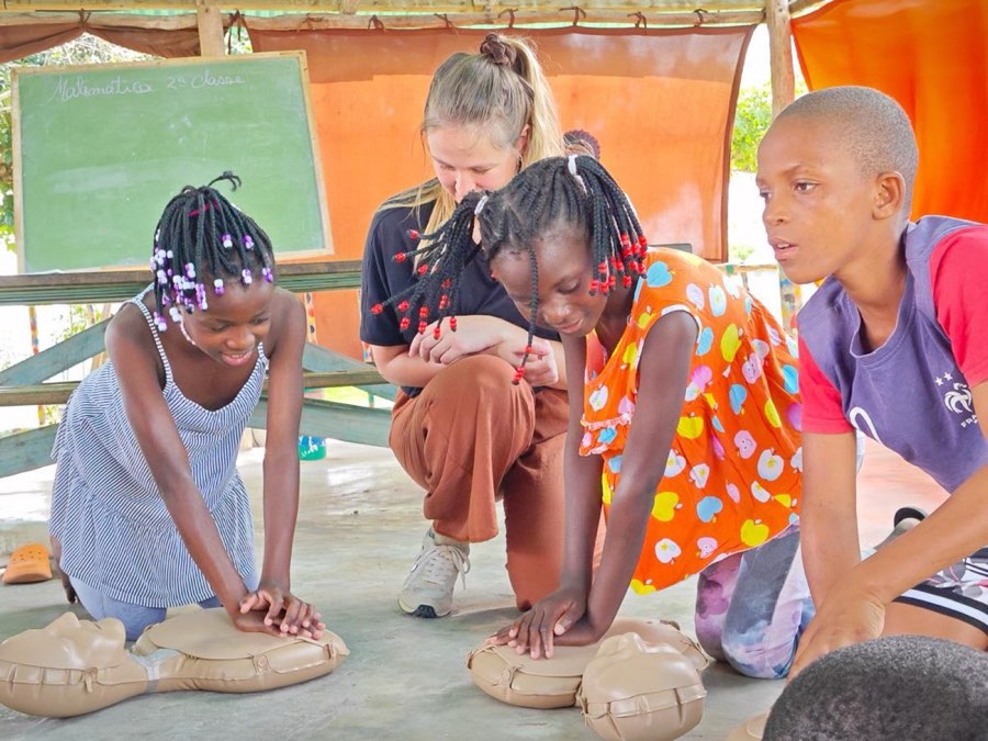 Children and a volunteer practising first aid together
